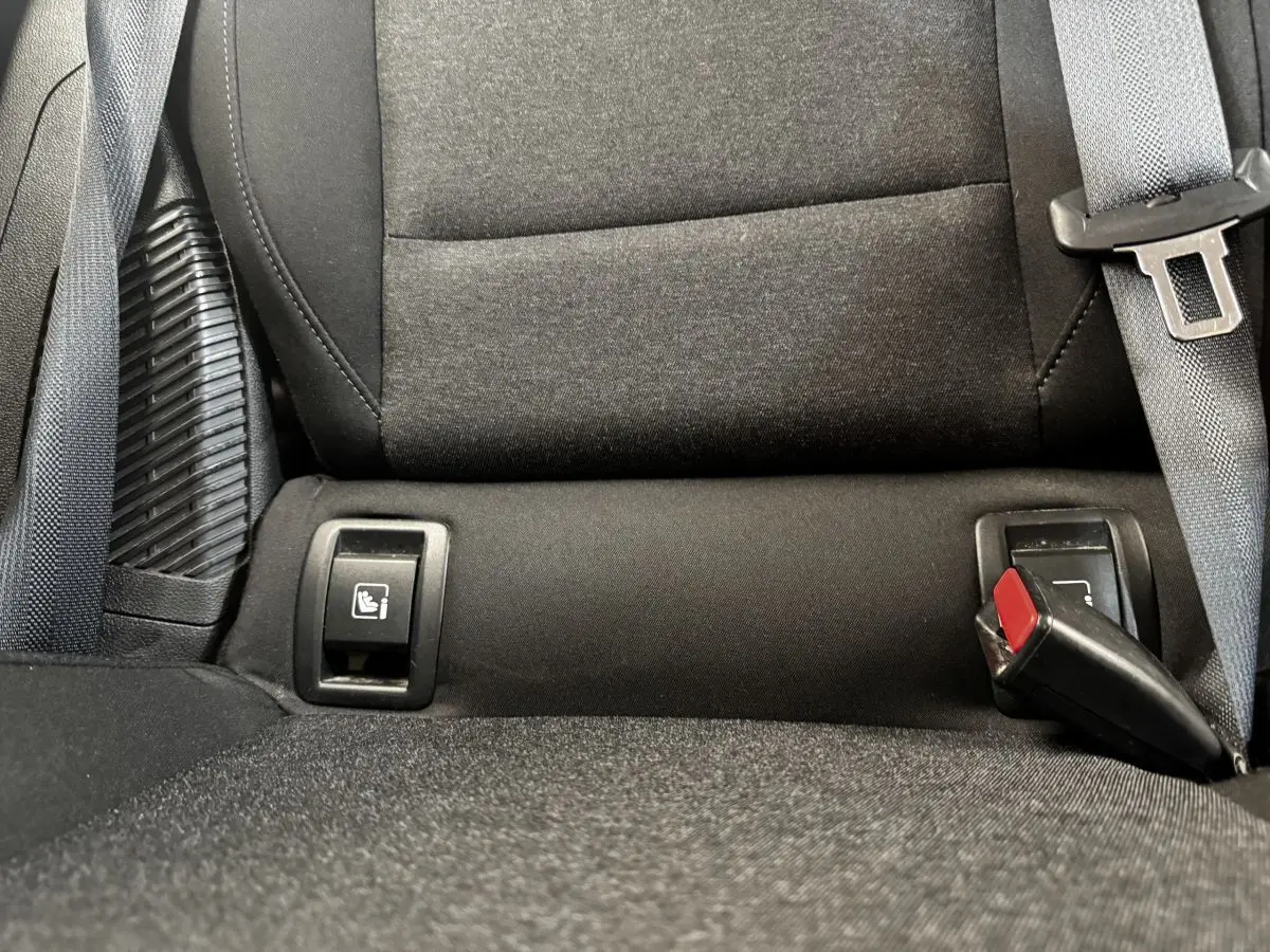Gros plan sur la banquette arrière noire de la Renault Clio Business E-TECH 140, montrant les attaches Isofix et la ceinture de sécurité.