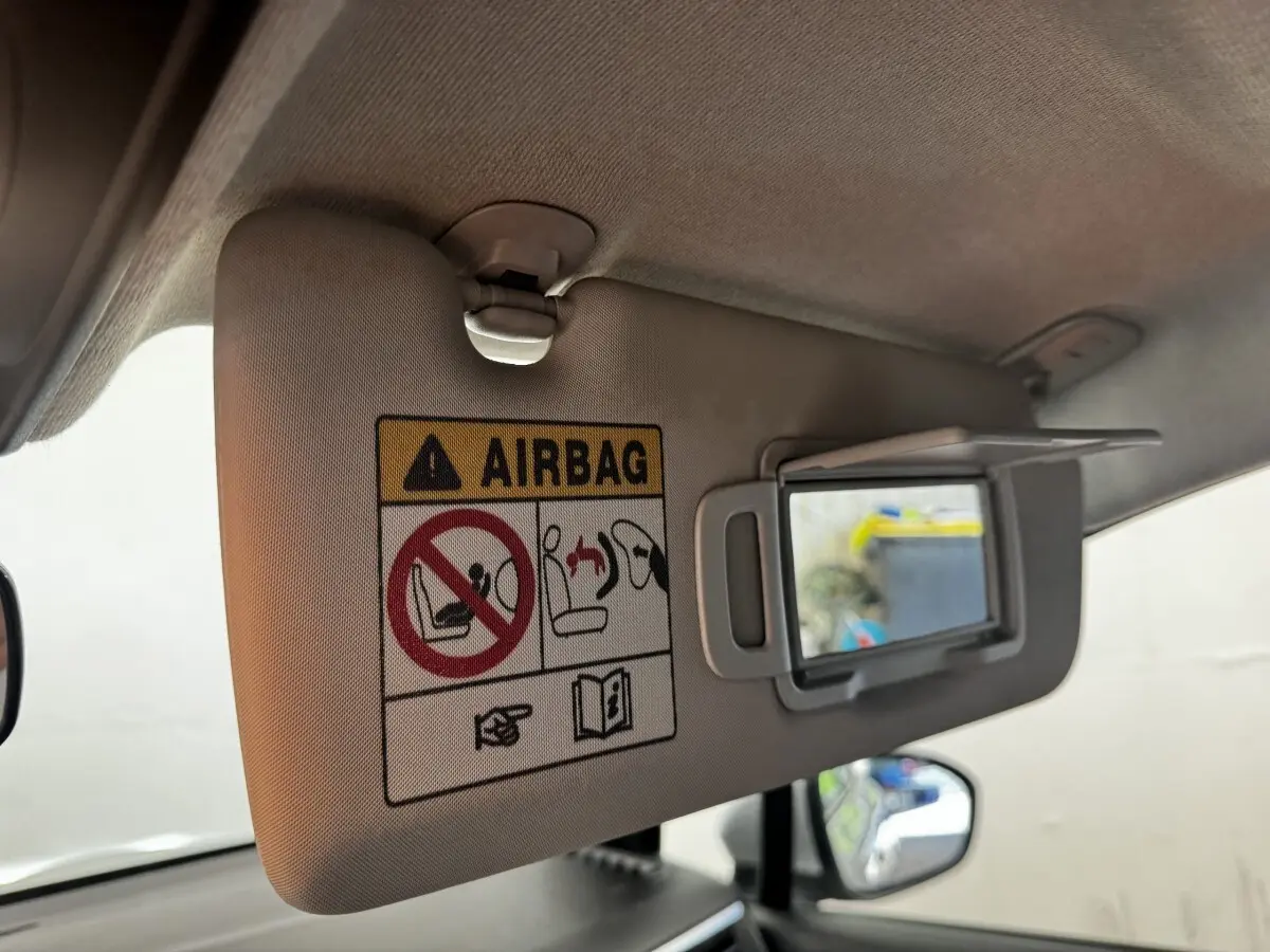 Détail du pare-soleil côté conducteur avec miroir de courtoisie ouvert et avertissement airbag dans une Renault Clio gris clair.
