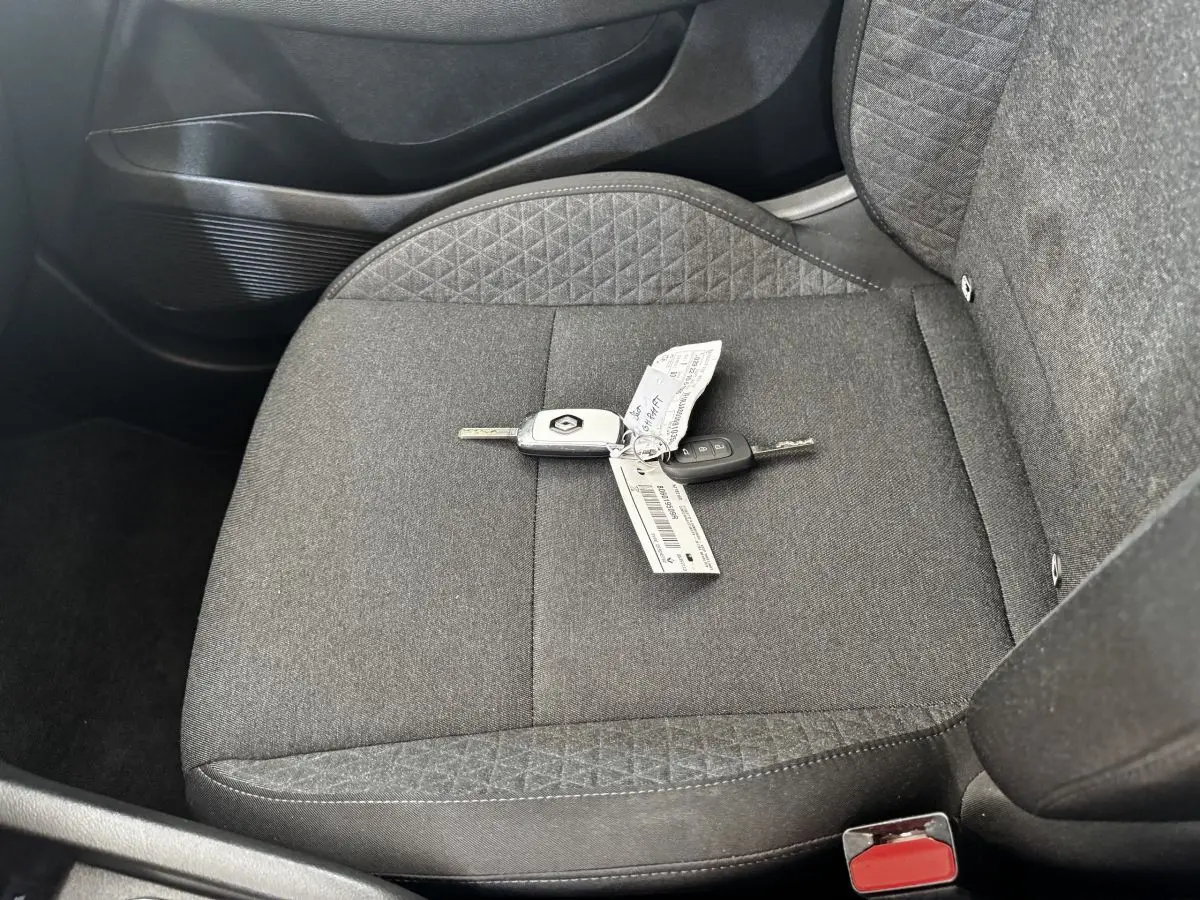 Gros plan sur la clé Renault posée sur le siège avant droit en tissu gris foncé de la Clio Business E-TECH 2022.