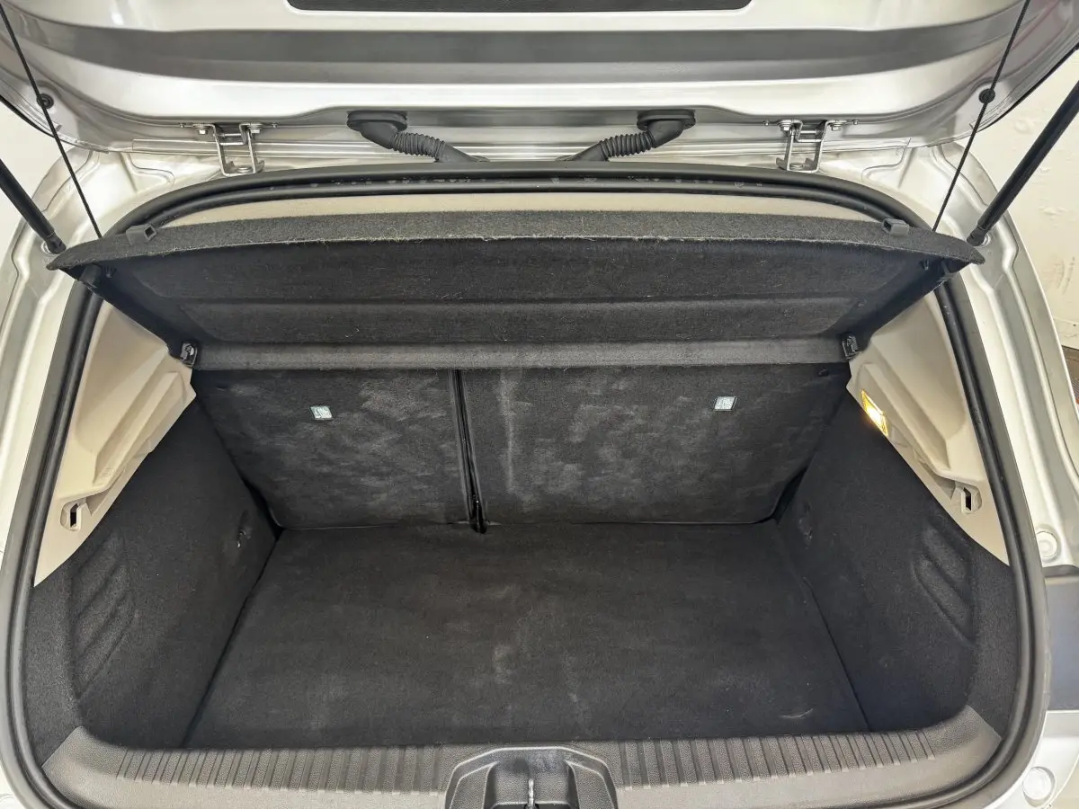 Coffre ouvert vu de l'arrière d'une Renault Clio Business E-TECH 140 gris clair, montrant l'espace de chargement vide.