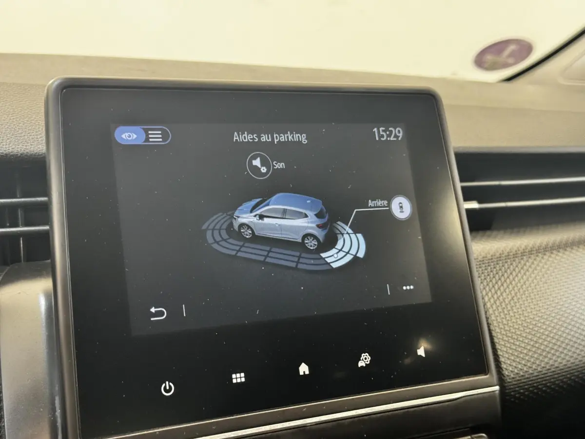 Écran tactile central montrant l’aide au parking d’une Renault Clio Business E-TECH 140 gris clair, vue intérieure.