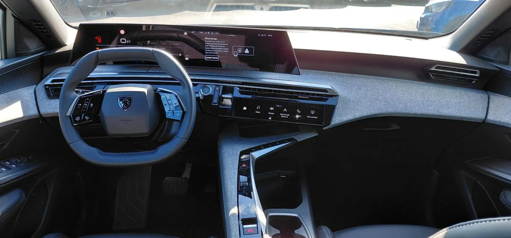 Vue intérieure du tableau de bord et volant du Peugeot 5008 Hybrid 2025 avec écran numérique large et finition tissu gris.