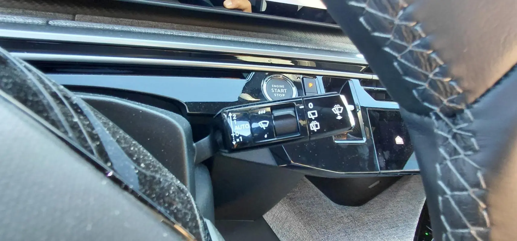 Gros plan sur la commande d'essuie-glace et le bouton start/stop du tableau de bord du Peugeot 5008 Hybrid blanc 2025.
