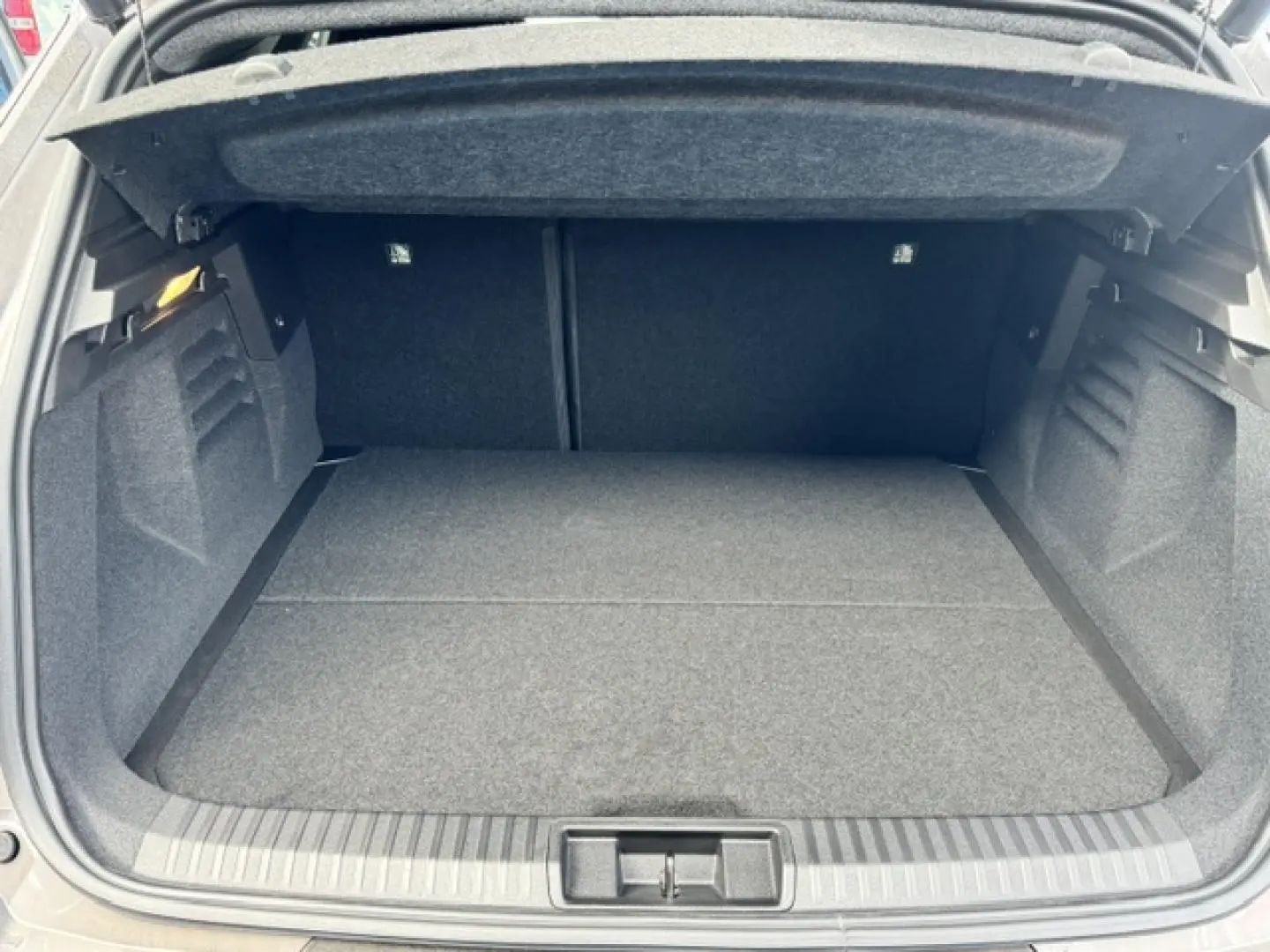 Coffre ouvert vu de face d'une Renault SYMBIOZ gris Cassiopée métallisé, espace de chargement vide et propre.