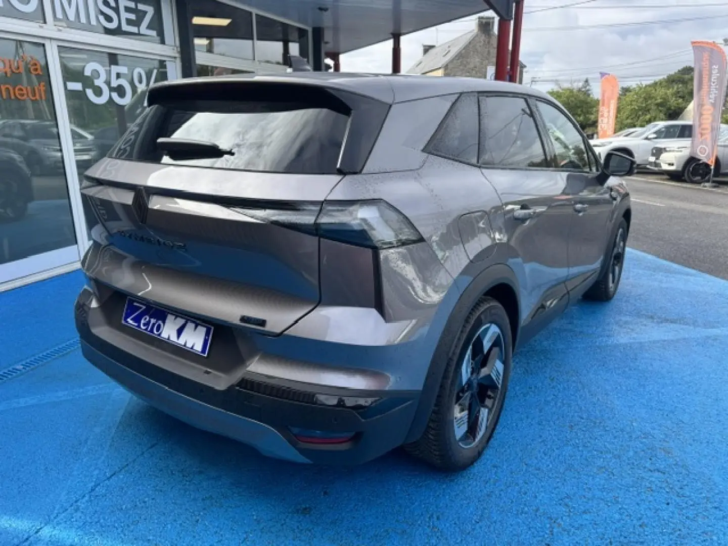 Vue 3/4 arrière droite du Renault Symbioz 2026 gris Cassiopée métallisé avec feux arrière LED et jantes alu noires.
