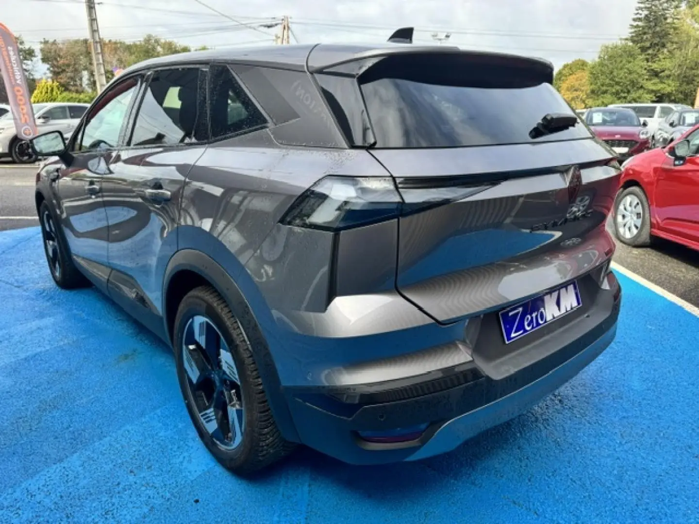 Vue 3/4 arrière droite d'un Renault Symbioz gris Cassiopée métallisé avec becquet et feux arrière LED distinctifs.