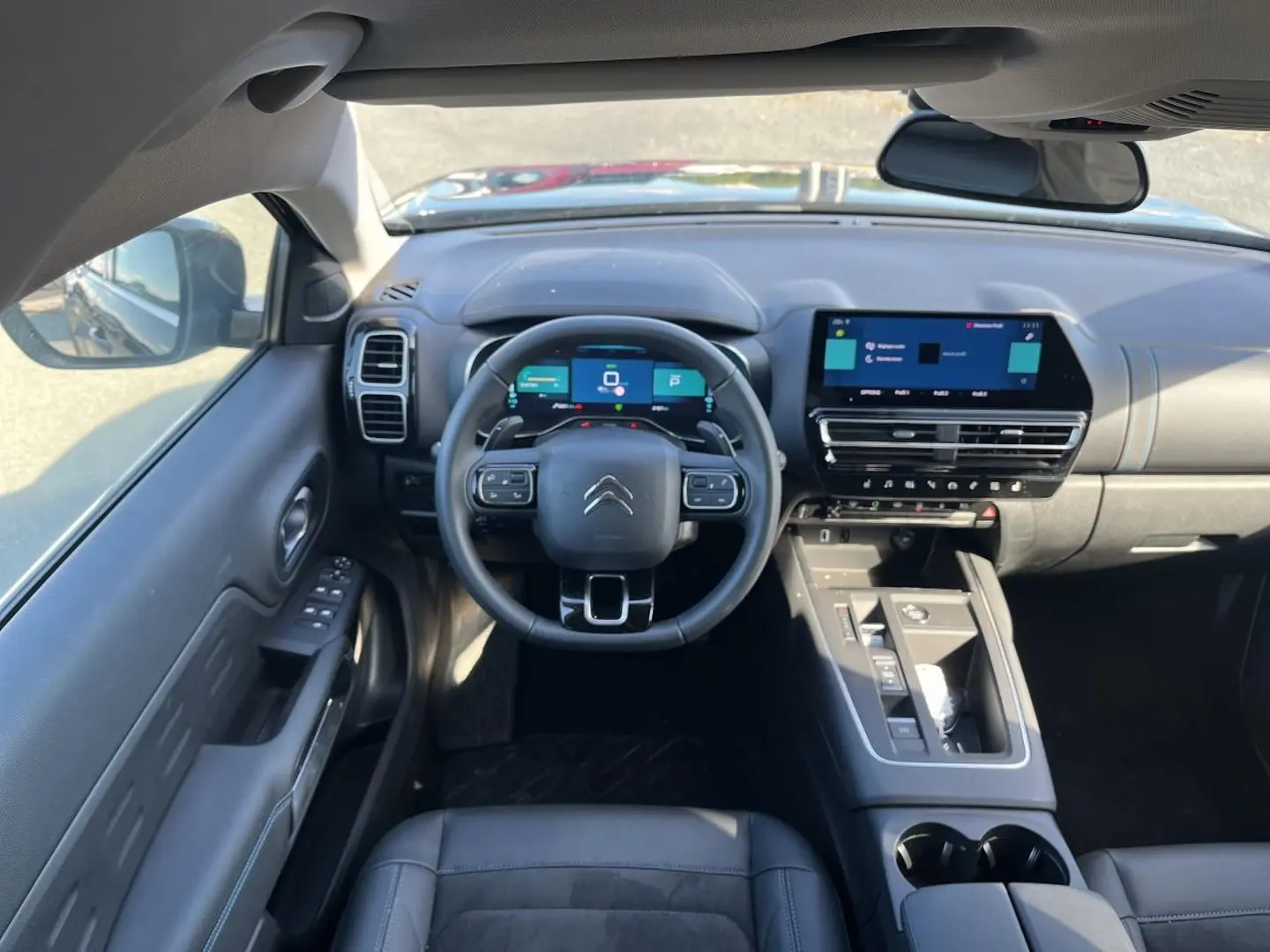 Vue intérieure avant du Citroën C5 Aircross noir 2024, tableau de bord et volant multifonction avec écran tactile.