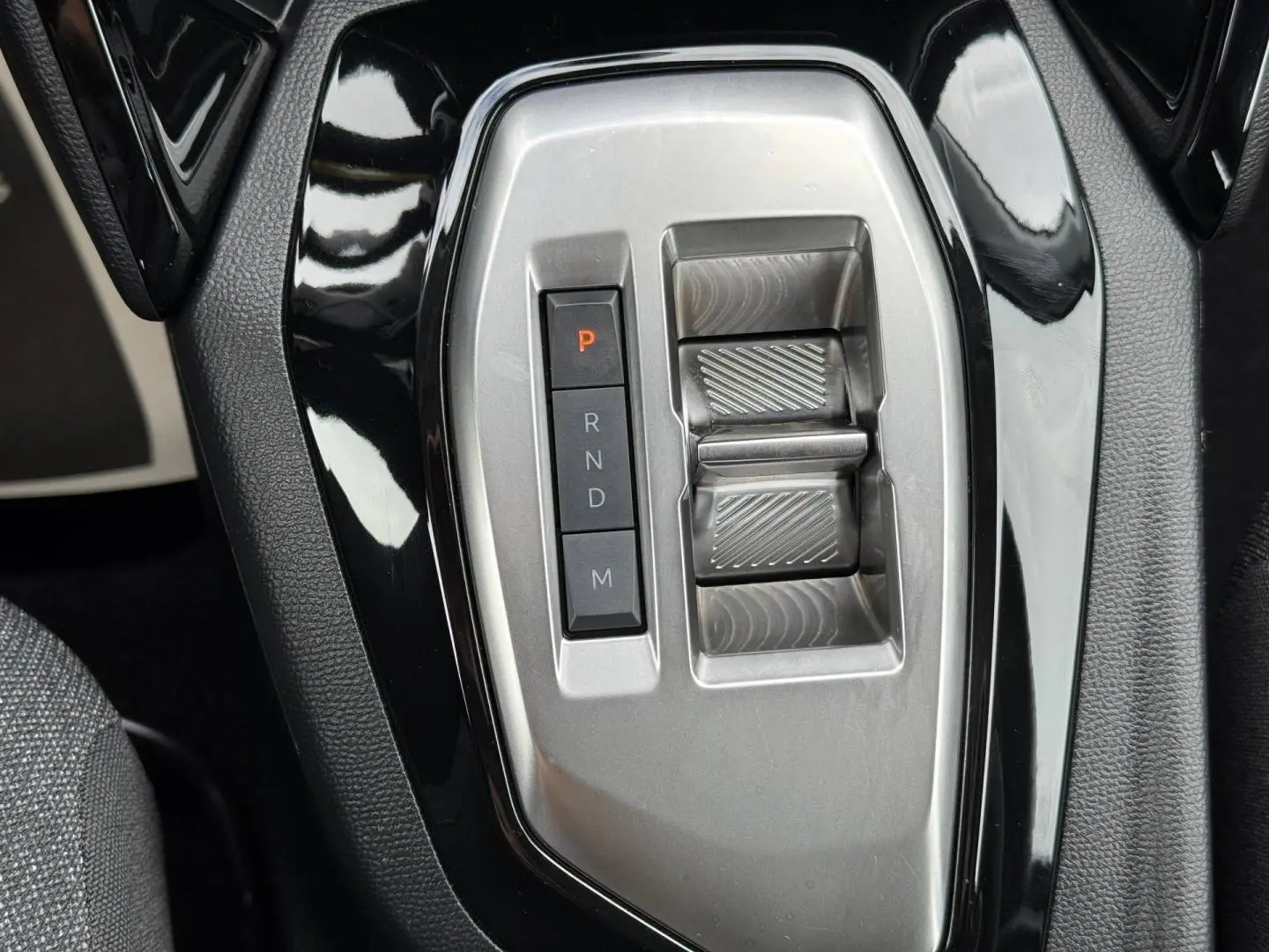 Gros plan sur la console centrale noire et argentée de la Peugeot 208 1.2 Hybrid 110ch avec sélecteur de boîte auto.