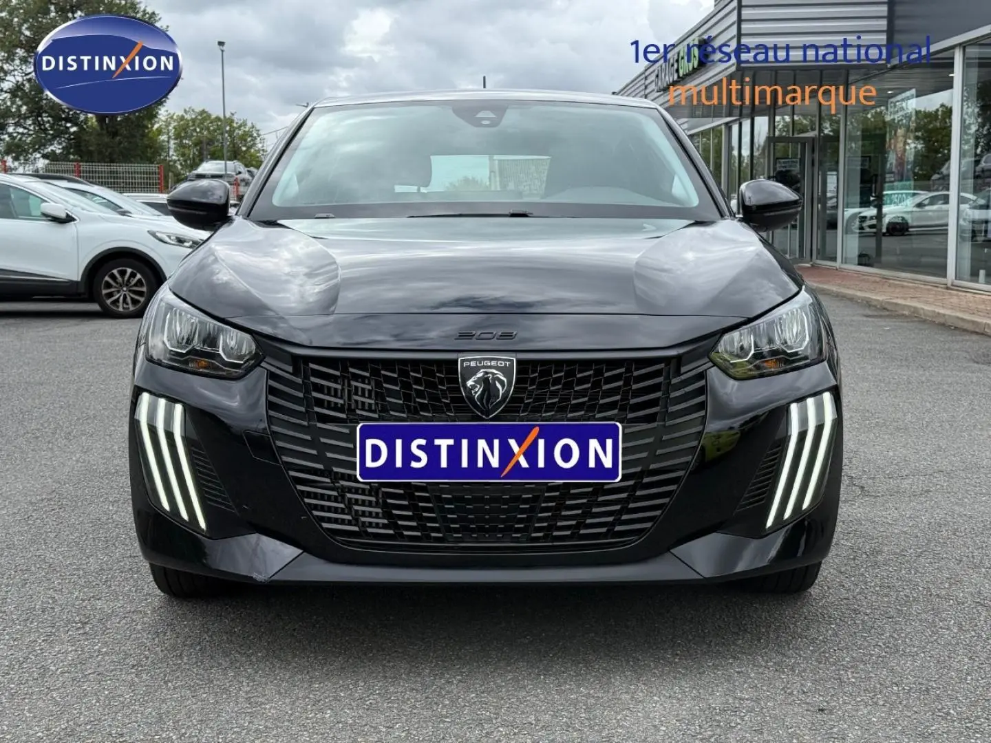 Vue frontale d'une Peugeot 208 noire Perla Nera avec phares LED verticaux distinctifs, sur parking extérieur.