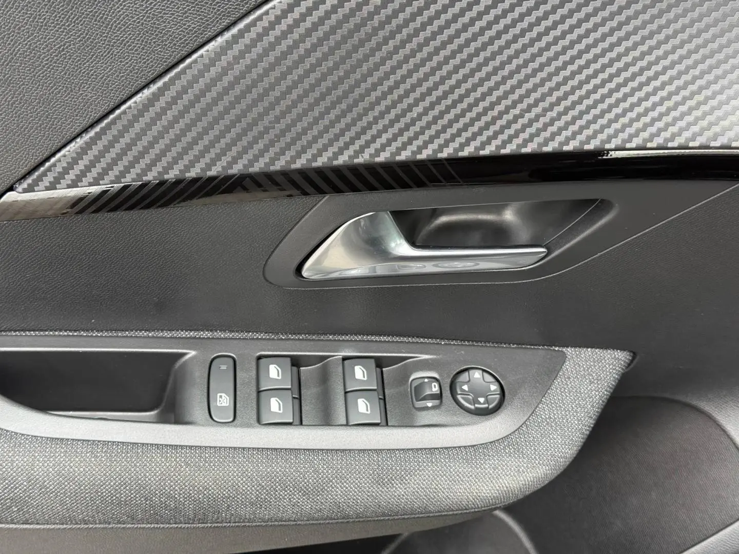 Détail de la porte avant gauche intérieure de la Peugeot 208 noire avec commandes des vitres et poignée argentée.