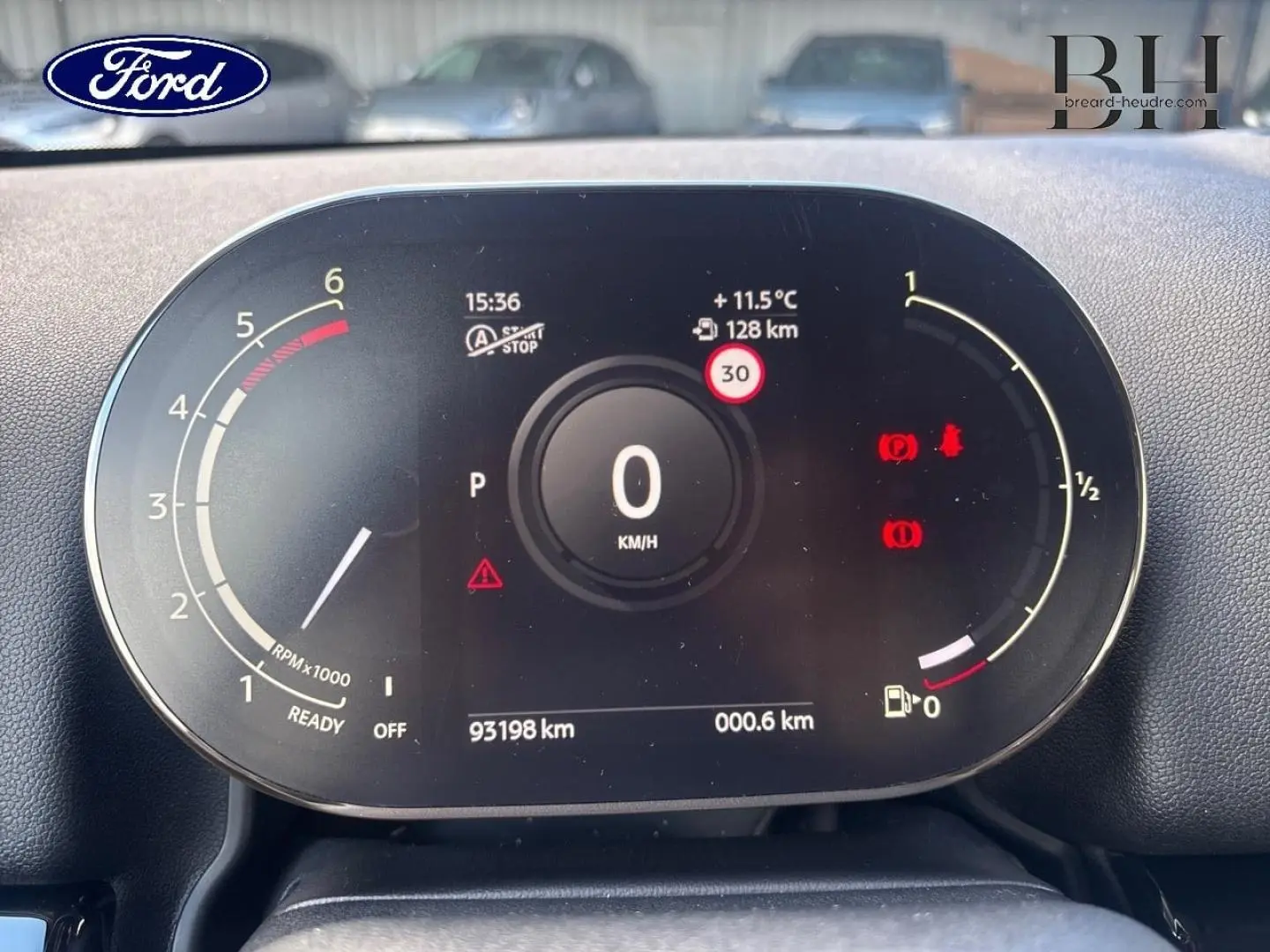 Vue rapprochée du tableau de bord numérique d'une MINI Countryman noire, affichant la vitesse à 0 km/h et divers indicateurs.