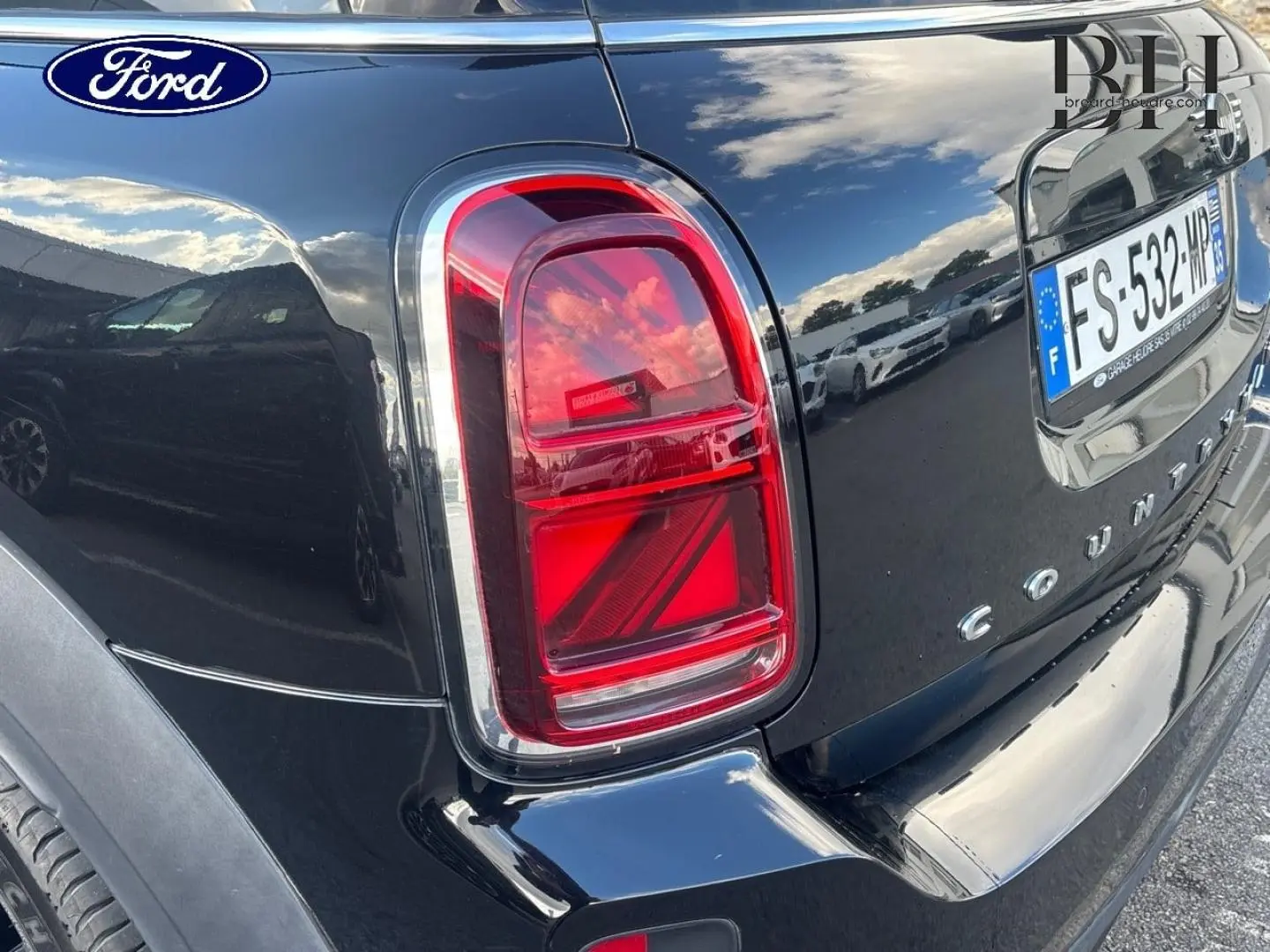 Feu arrière droit et partie arrière en 3/4 d’un MINI Countryman Cooper D noir Midnight avec bandes grises sur capot.