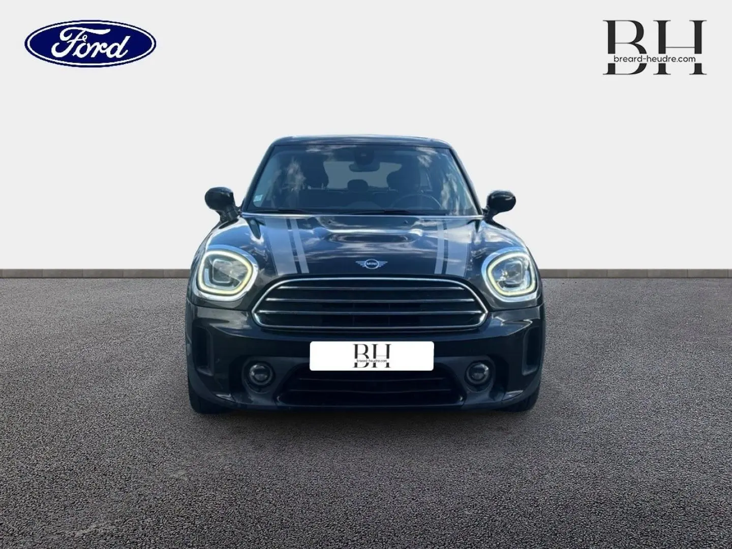 Vue avant d'une MINI Countryman Cooper D noire Midnight Black avec bandes grises sur capot et phares LED allumés.