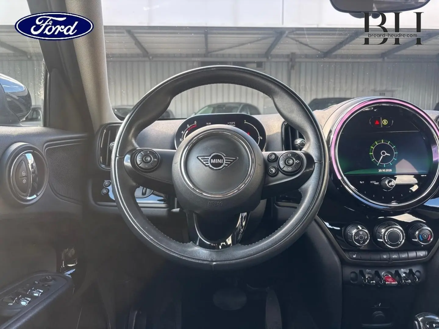 Vue intérieure centrée sur le volant cuir MINI avec tableau de bord et écran tactile rond illuminé.