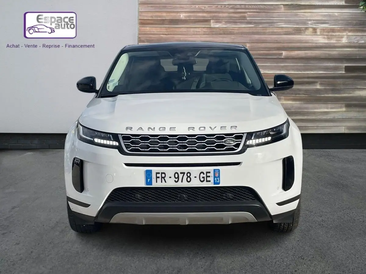 Vue frontale d'un Range Rover Evoque blanc 2020 avec calandre noire et phares LED allumés.