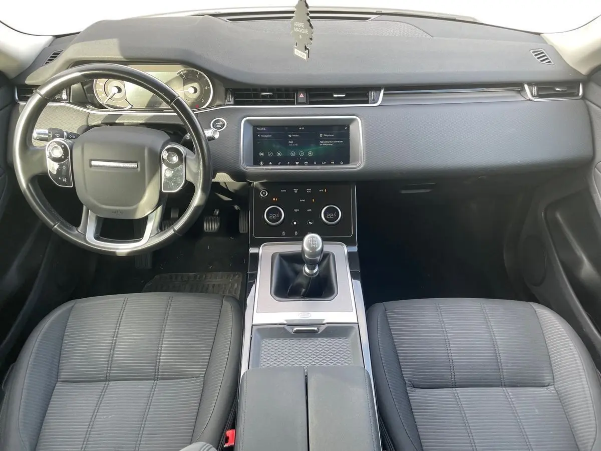 Intérieur du Range Rover Evoque 2020 blanc, vue de face sur le tableau de bord et levier de vitesses manuel.
