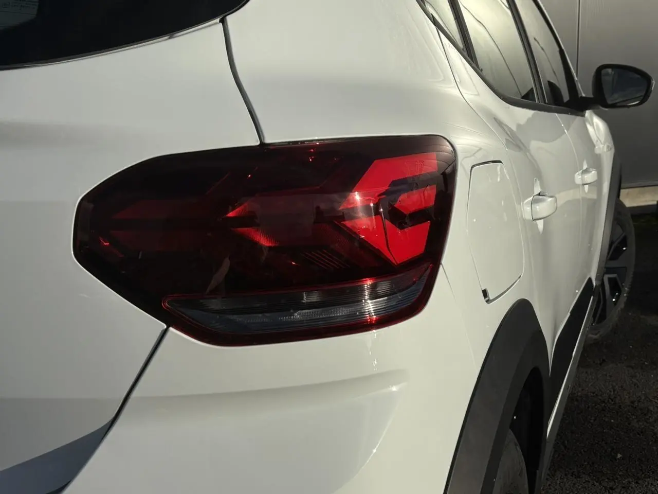 Feu arrière droit en gros plan sur Dacia Sandero Stepway blanc glacier, vue latérale arrière droite.