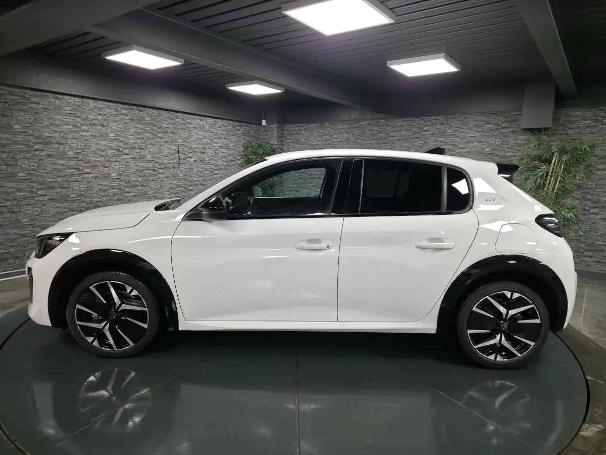 Peugeot 208 GT blanche vue de profil gauche, avec jantes alliage bi-ton et élargisseurs d'ailes noirs brillants.