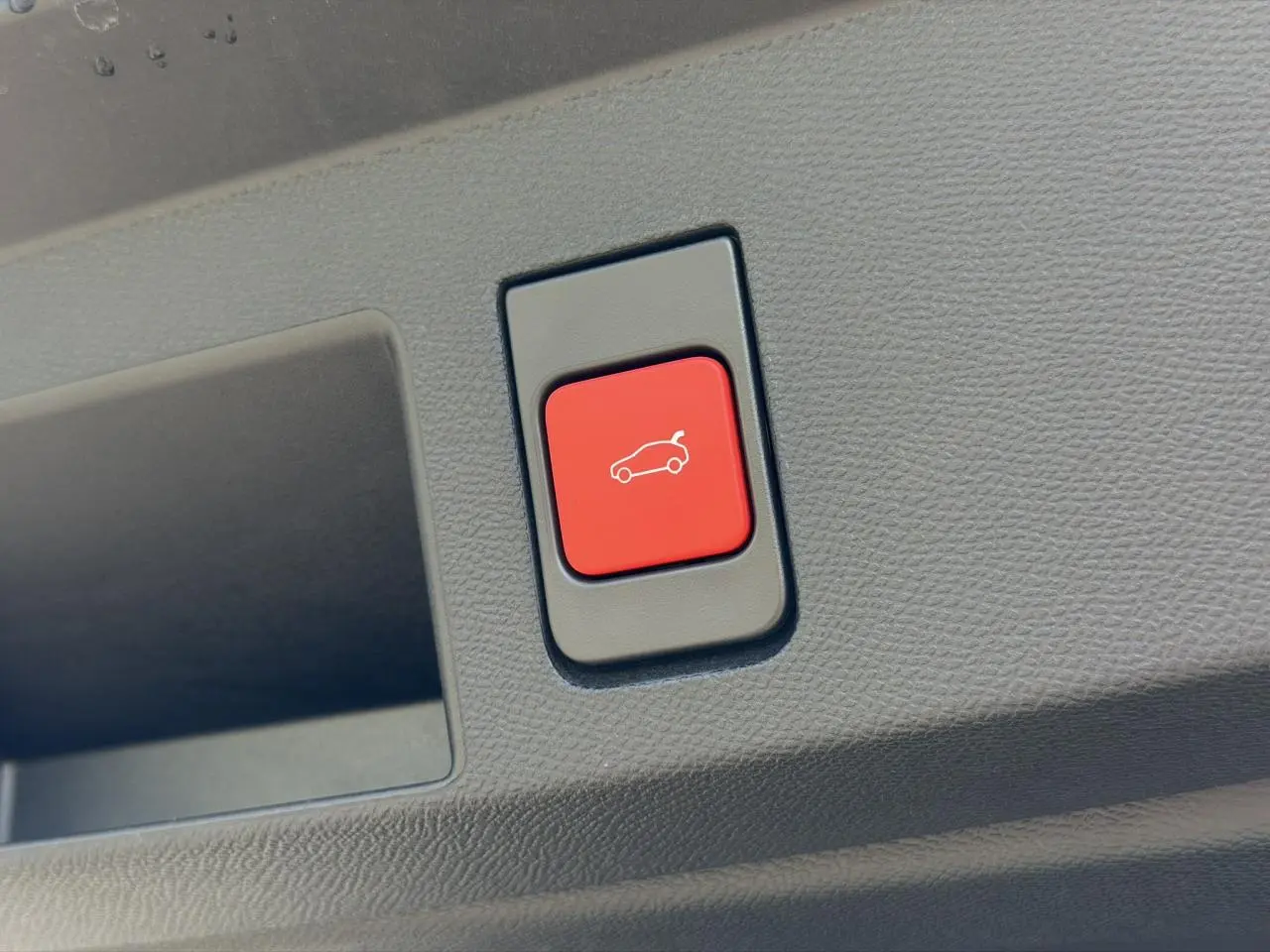 Bouton rouge d'ouverture électrique du hayon sur le panneau intérieur d'un Citroën C5 Aircross 2026 gris Platinium.