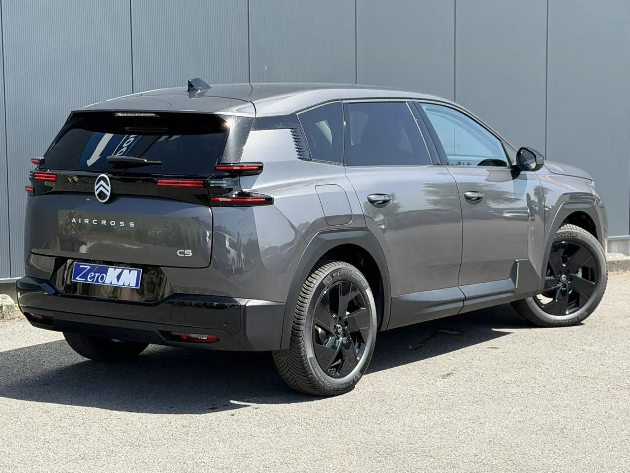 Vue 3/4 arrière droite d'un Citroën C5 Aircross gris Platinium avec jantes noires et feux arrière LED horizontaux.