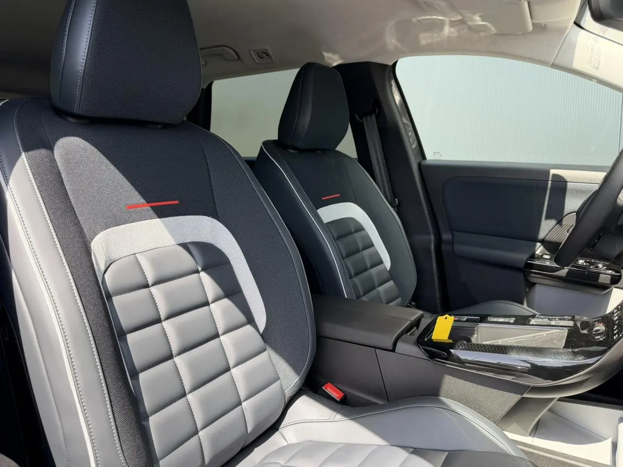 Vue intérieure des sièges avant gris et noirs avec surpiqûres blanches du Citroën C5 Aircross 2026, console centrale visible.