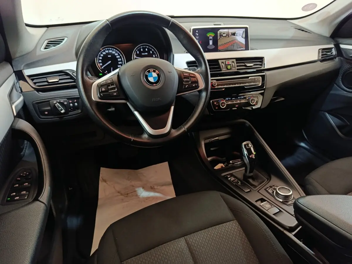 Intérieur BMW X1 sDrive18i 2021 vu de face, tableau de bord noir avec écran multimédia et volant cuir multifonctions.