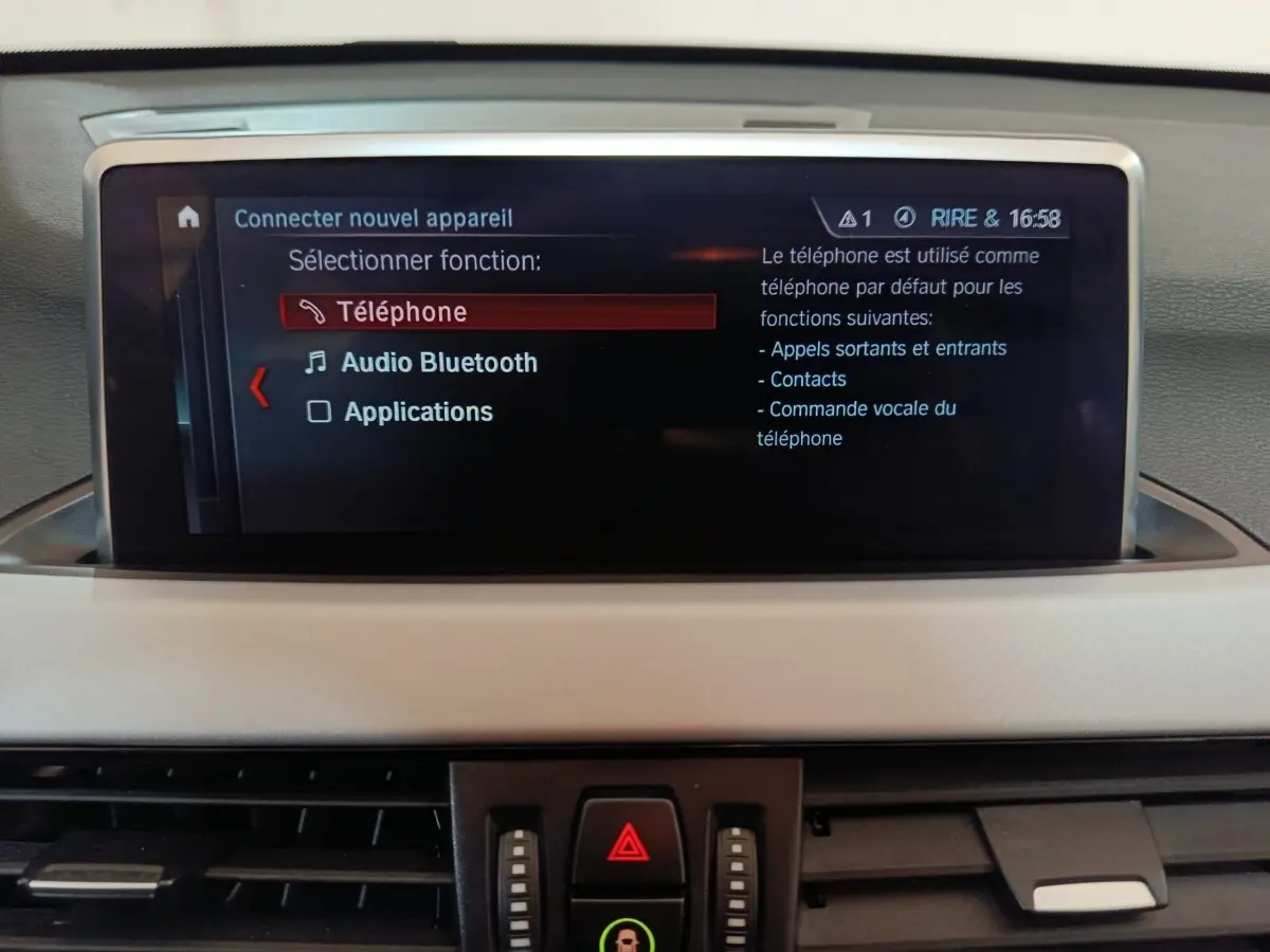 Écran central du tableau de bord de BMW X1 gris foncé, affichant le menu Bluetooth et téléphone.