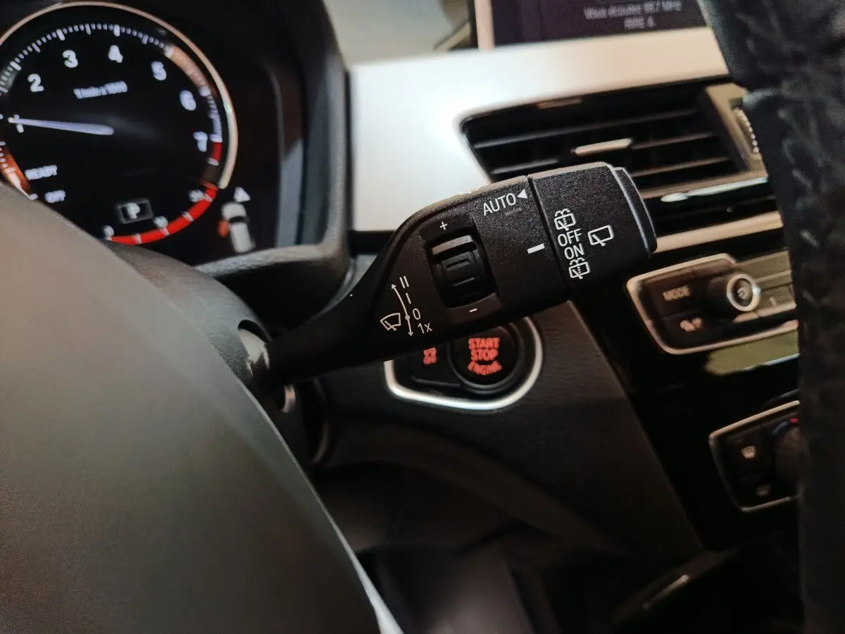 Gros plan sur la commande d’essuie-glace à gauche du volant cuir dans l’habitacle du BMW X1 gris foncé 2021.