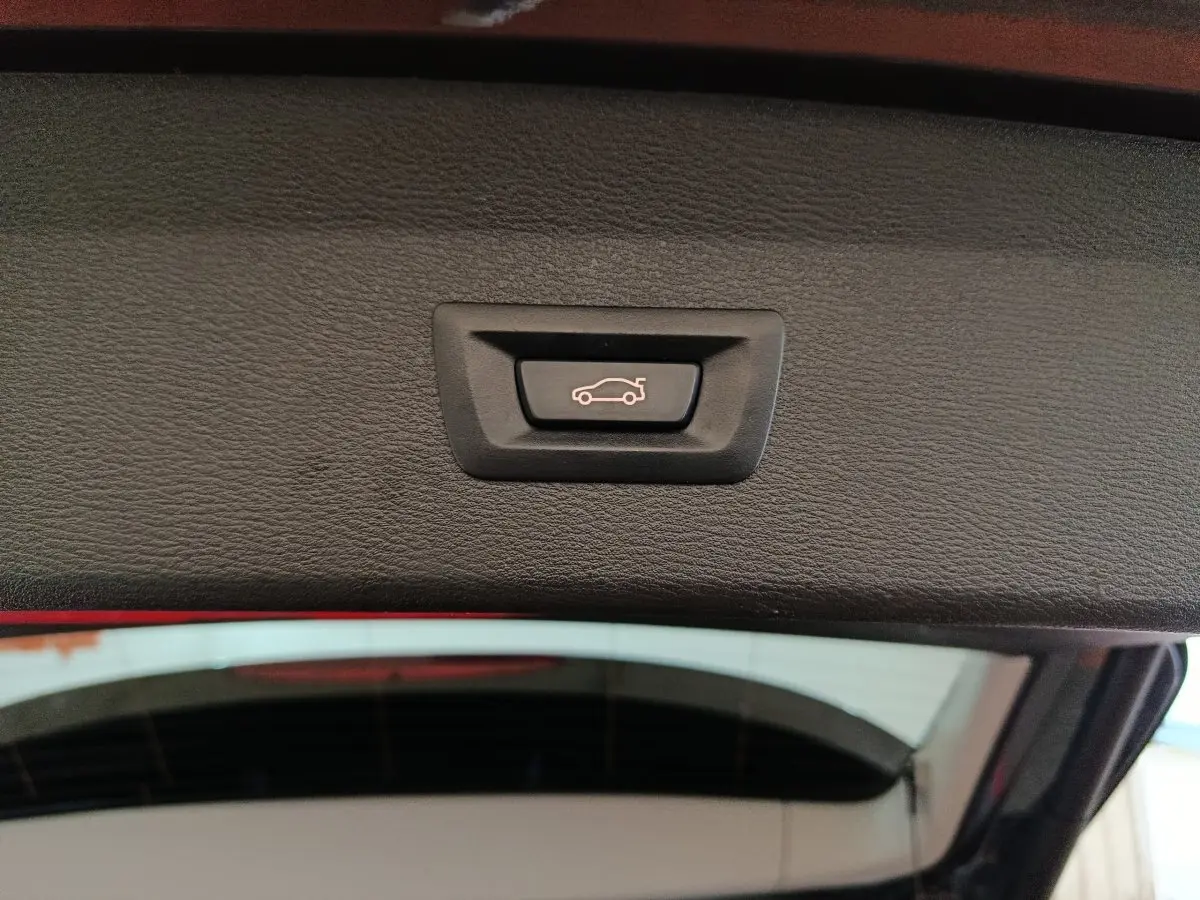 Bouton de fermeture électrique du coffre visible sur la partie intérieure du hayon d’un BMW X1 gris foncé.