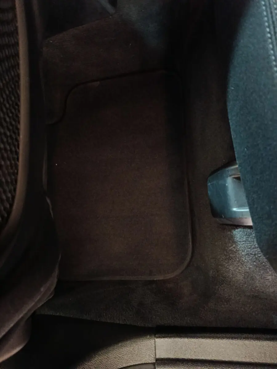 Vue rapprochée du tapis de sol noir côté passager arrière d'un BMW X1 sDrive18i Lounge gris foncé.