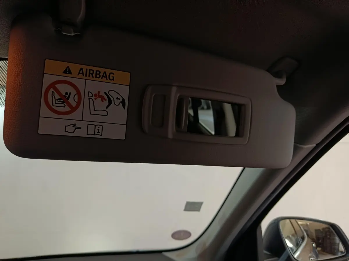 Détail du pare-soleil côté conducteur avec miroir et avertissement airbag dans un BMW X1 gris foncé 2021.