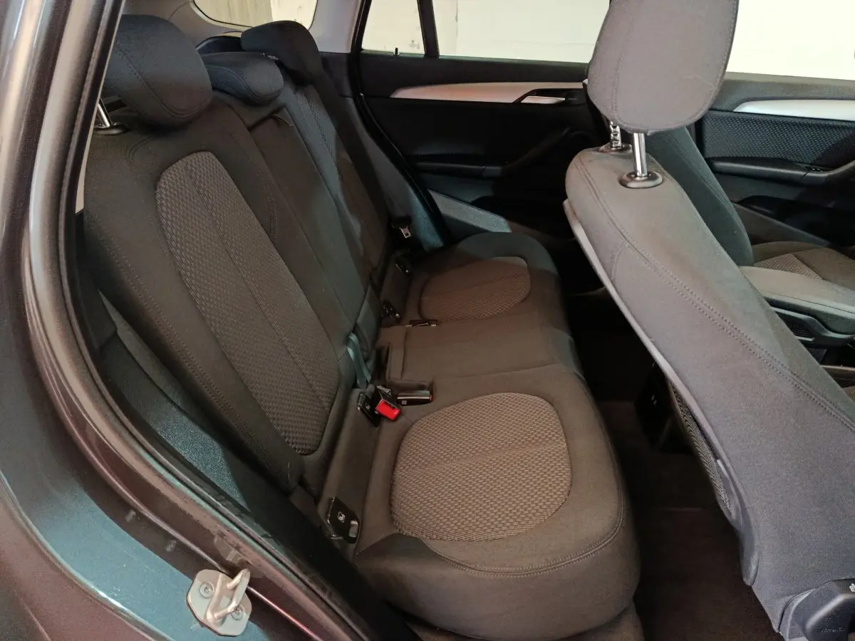 Vue intérieure côté gauche montrant la banquette arrière grise du BMW X1 sDrive18i Lounge 2021 avec sièges tissu.