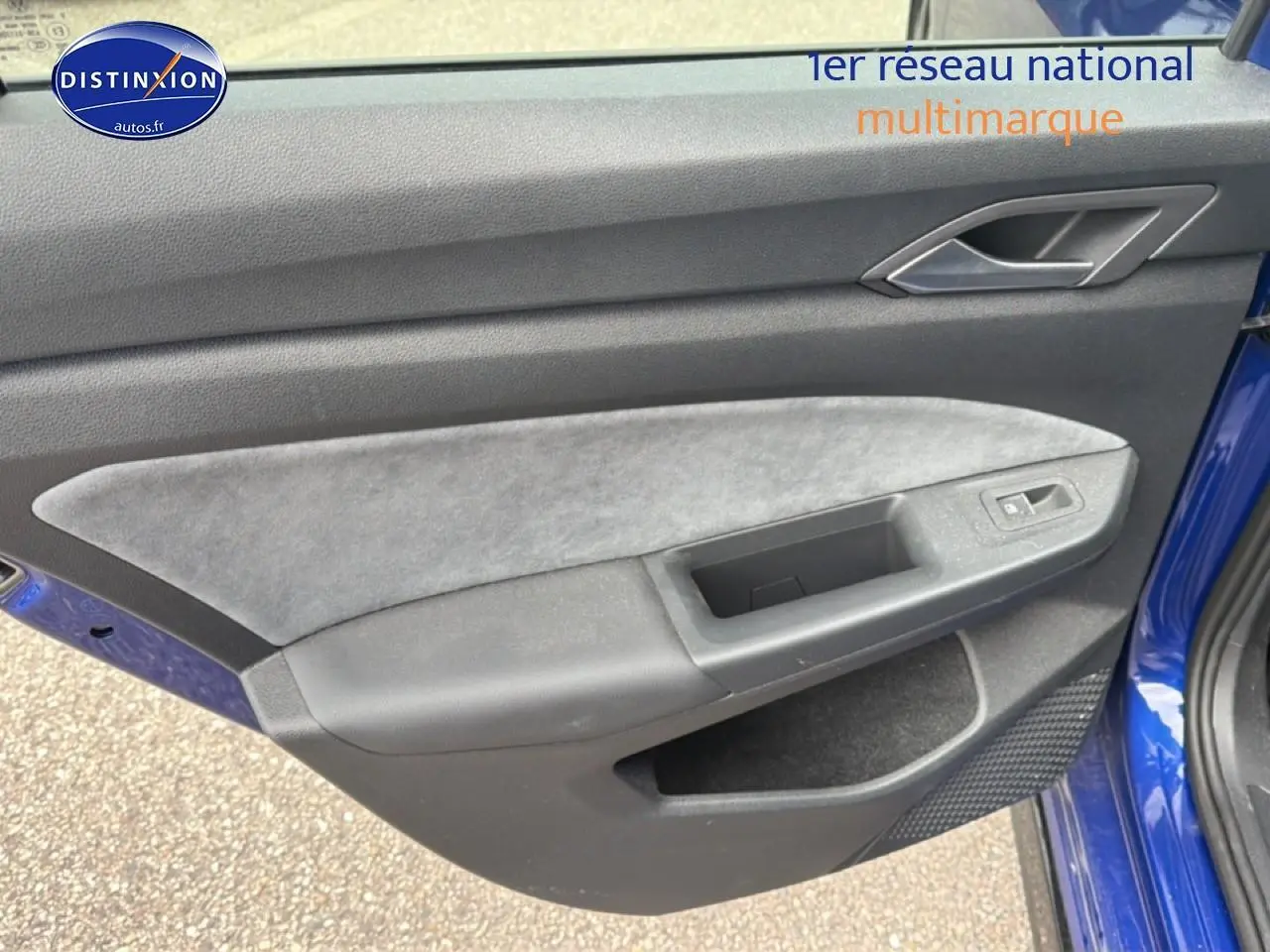 Vue rapprochée de la porte avant gauche bleu de la Volkswagen Golf 2024 avec garniture grise et commandes de vitre.
