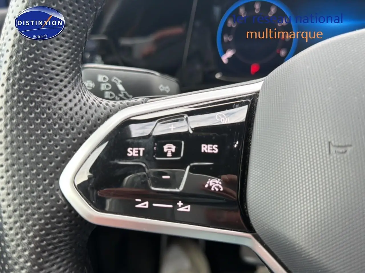 Gros plan sur les commandes multifonctions noires à gauche du volant perforé gris d’une Volkswagen Golf bleue 2024.