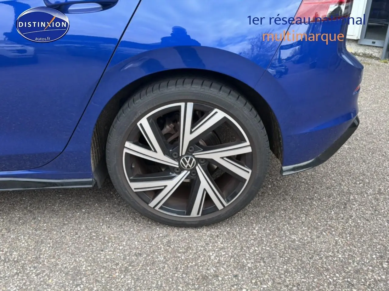 Gros plan sur la roue arrière droite et la carrosserie bleue d'une Volkswagen Golf 2024 finition R-Line.