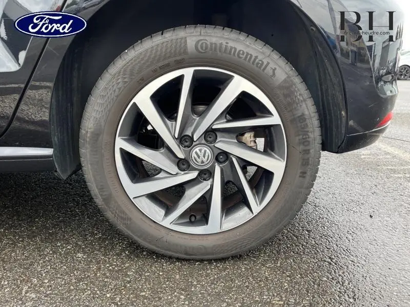 Gros plan sur la roue arrière droite d'une Volkswagen Polo noire avec jante alu à design moderne.