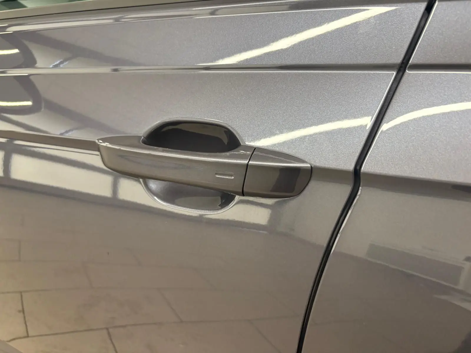 Poignée de porte côté gauche du Volkswagen Taigo gris cendré métallisé, vue rapprochée sur la finition lisse.