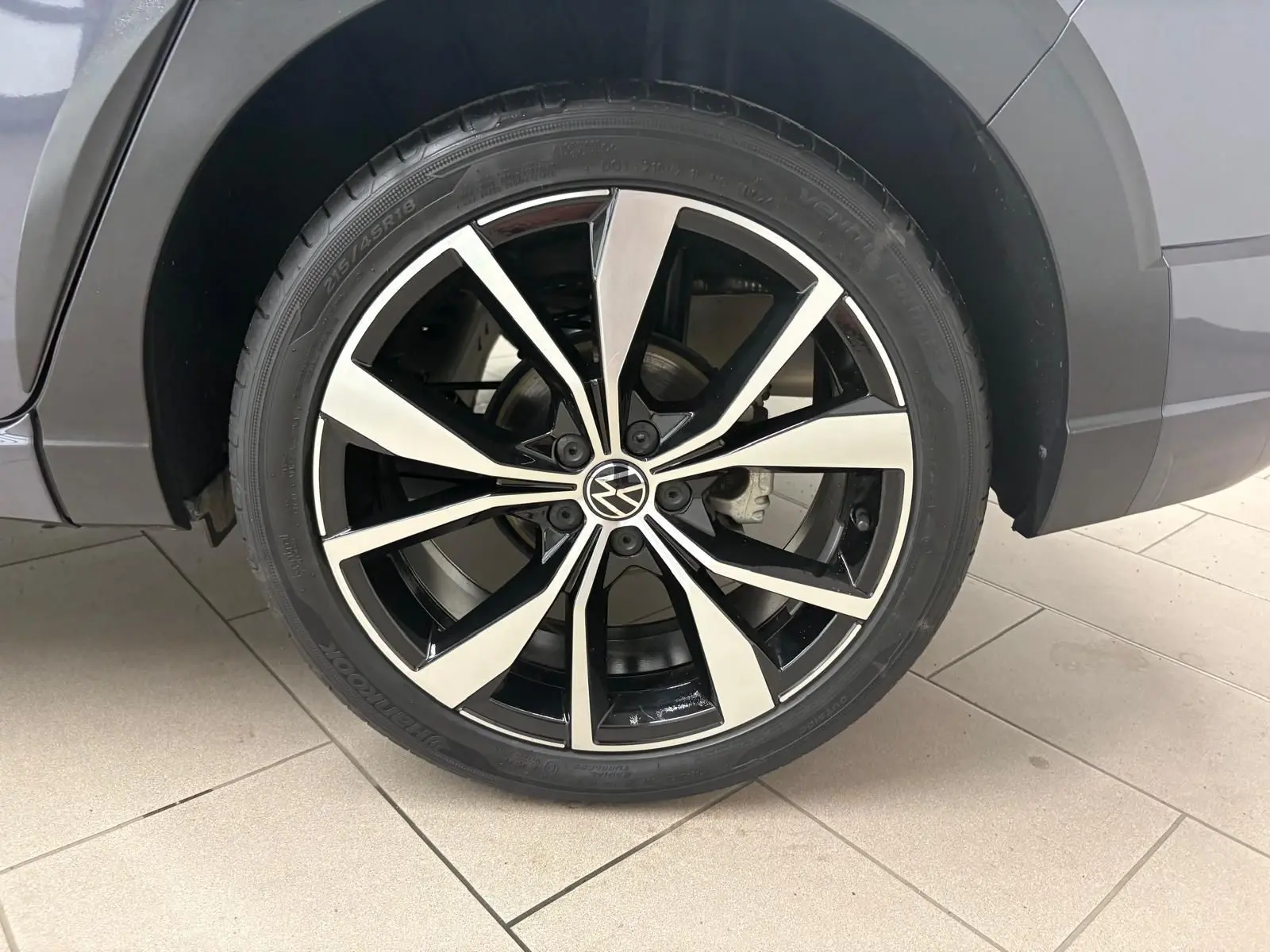 Gros plan sur la jante alliage noir et argent 18 pouces du côté gauche du Volkswagen Taigo gris cendré.