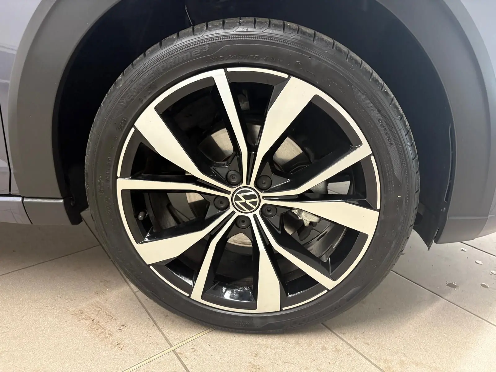 Gros plan sur la jante alliage noir et argent 18 pouces du Volkswagen Taigo gris cendré, avec logo VW central.