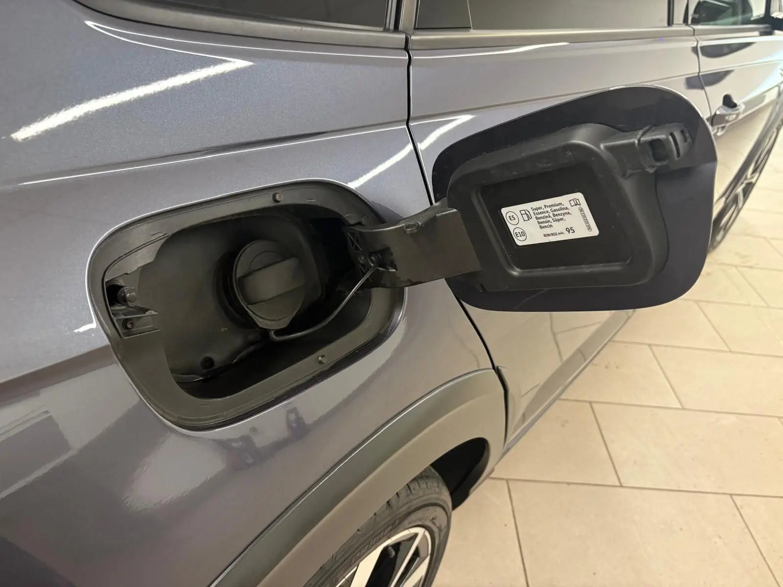 Gros plan sur la trappe à carburant ouverte côté gauche d’un Volkswagen Taigo gris cendré 2024.