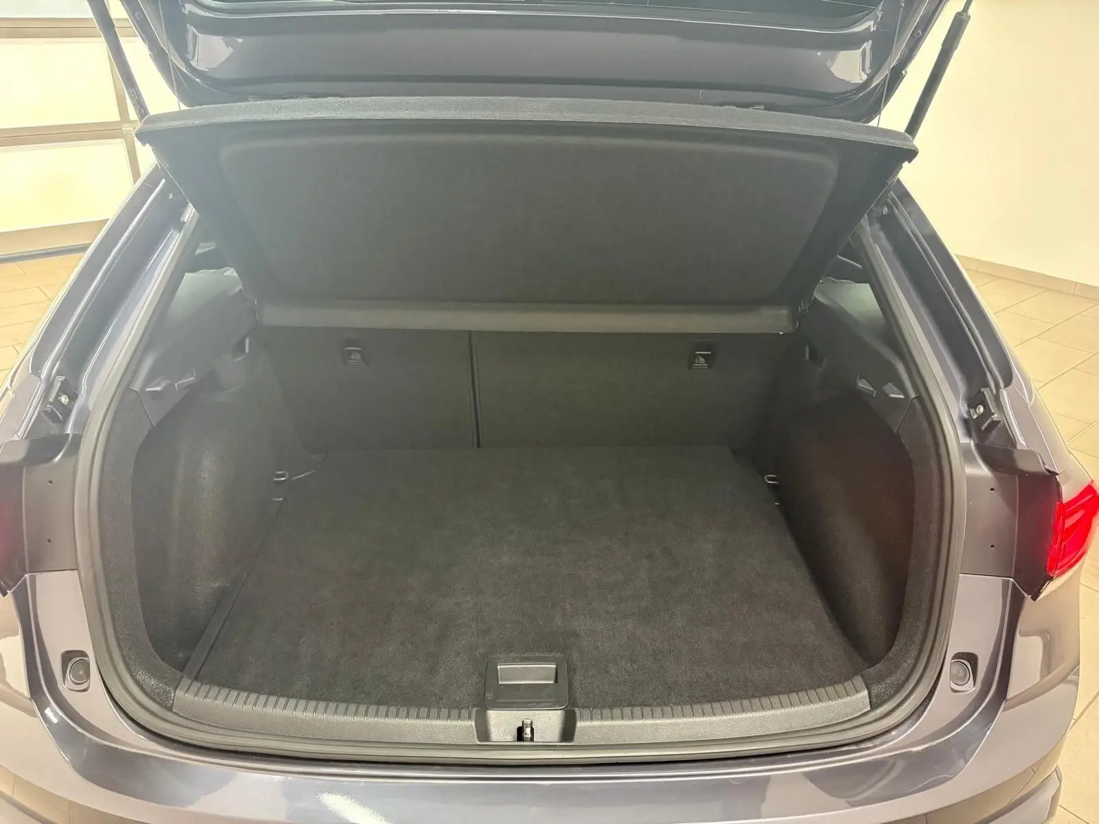 Coffre ouvert vu de l'arrière d'un Volkswagen Taigo gris cendré 2024, montrant l'espace de chargement vide.
