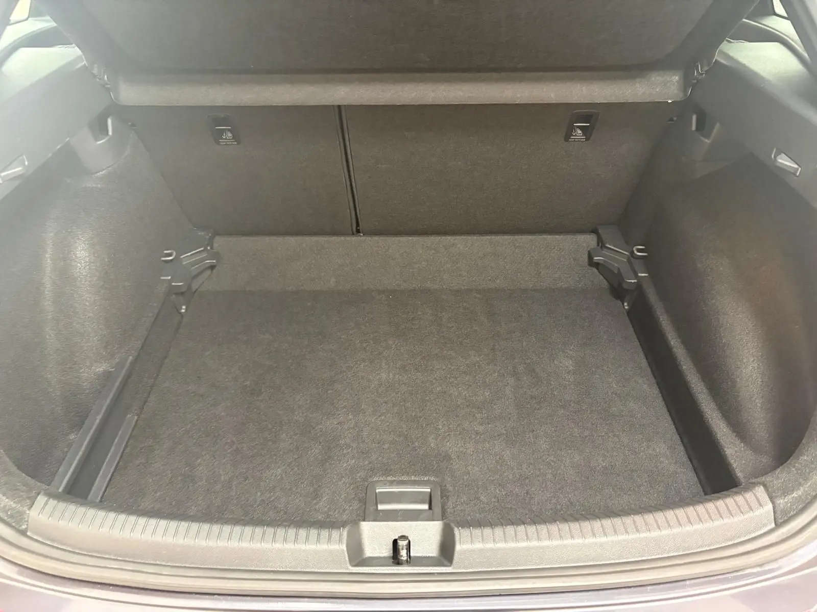 Coffre ouvert du Volkswagen Taigo gris cendré, montrant un espace de chargement propre et bien fini.