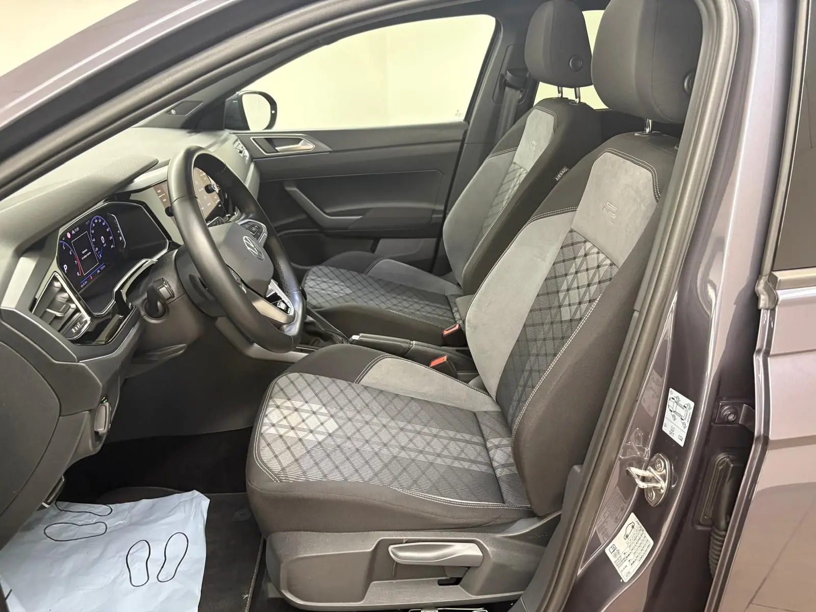 Vue intérieure côté conducteur du Volkswagen Taigo gris cendré, sièges avant en tissu et alcantara avec surpiqûres R-Line.