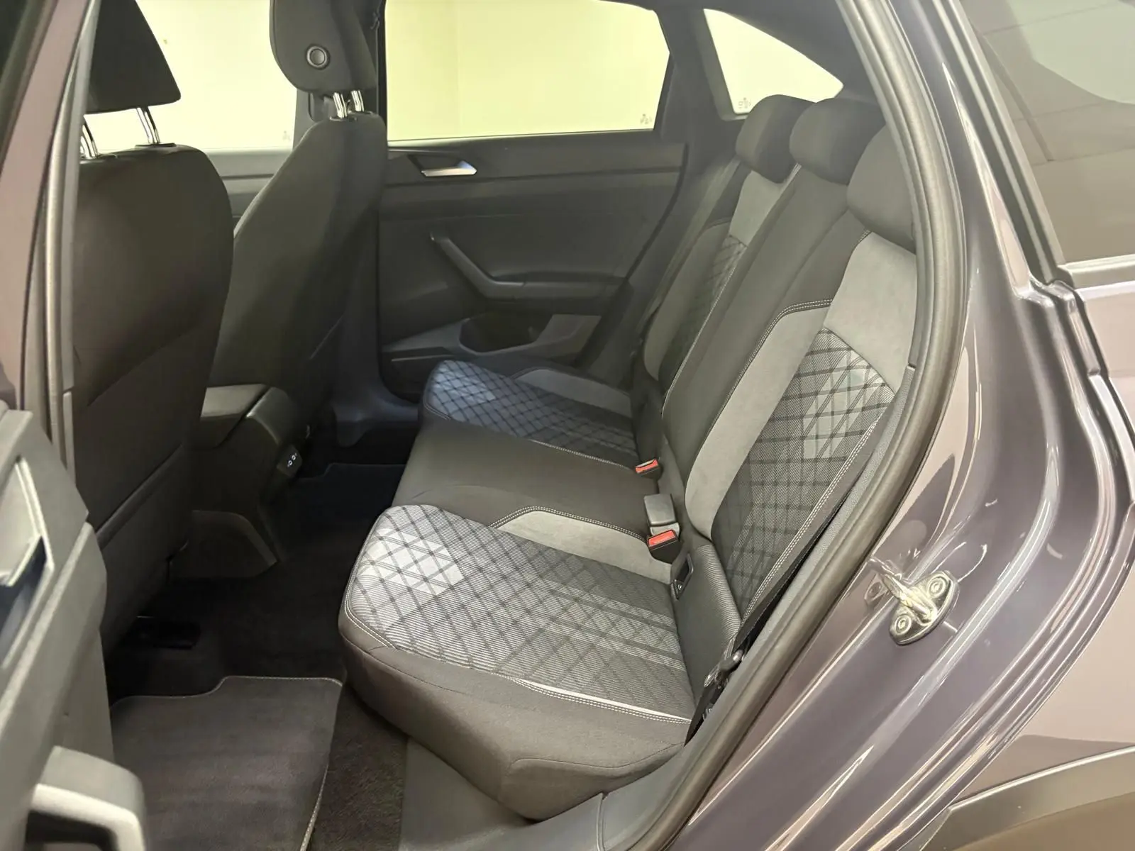 Vue intérieure arrière côté droit du Volkswagen Taigo gris cendré, montrant les sièges arrière en tissu à motif géométrique.