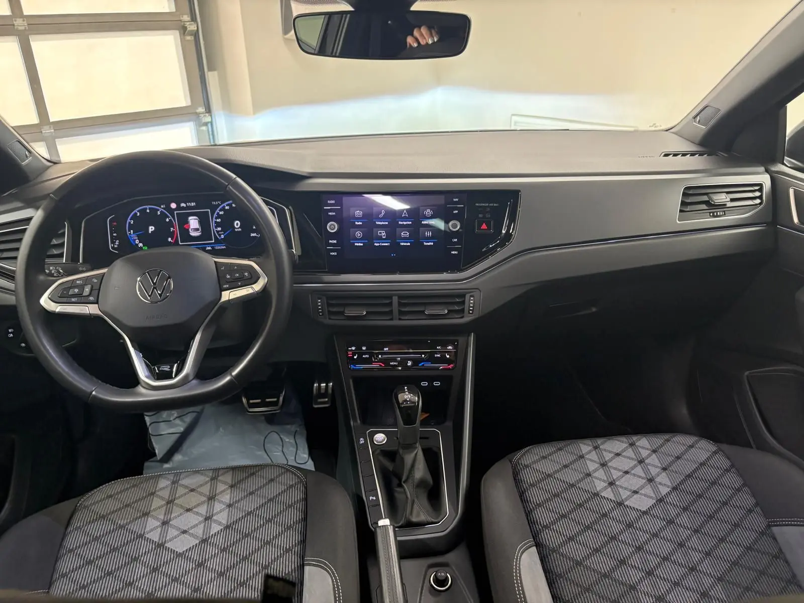 Vue intérieure avant du Volkswagen Taigo 1.5 TSI R-Line 2024, tableau de bord noir avec écran tactile et volant multifonction.