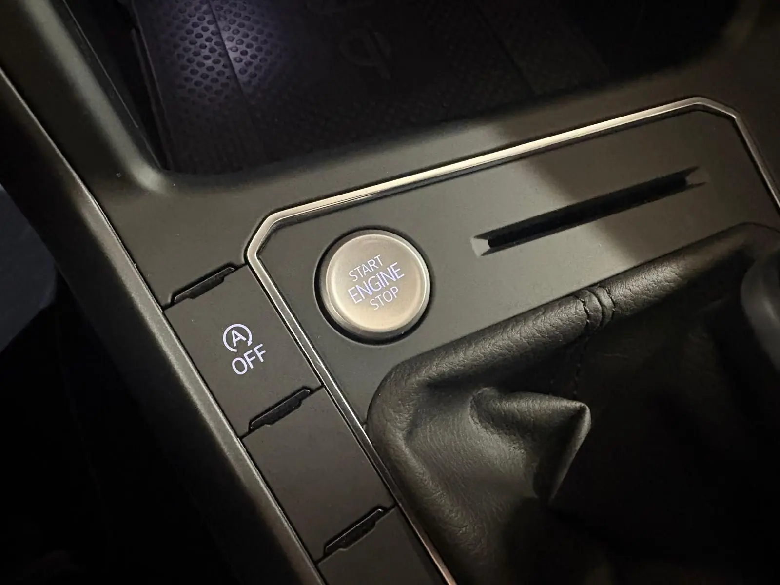 Gros plan sur le bouton start/stop moteur et commande auto start/stop dans la console centrale noire du Volkswagen Taigo.