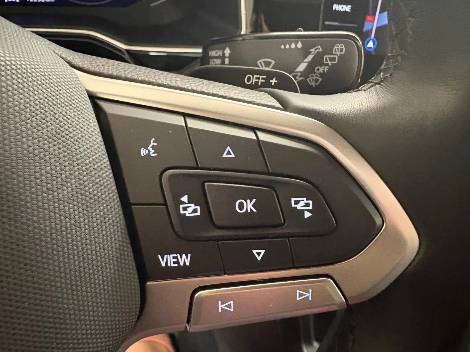 Gros plan sur les commandes au volant du Volkswagen Taigo gris cendré, avec boutons multifonctions rétroéclairés.