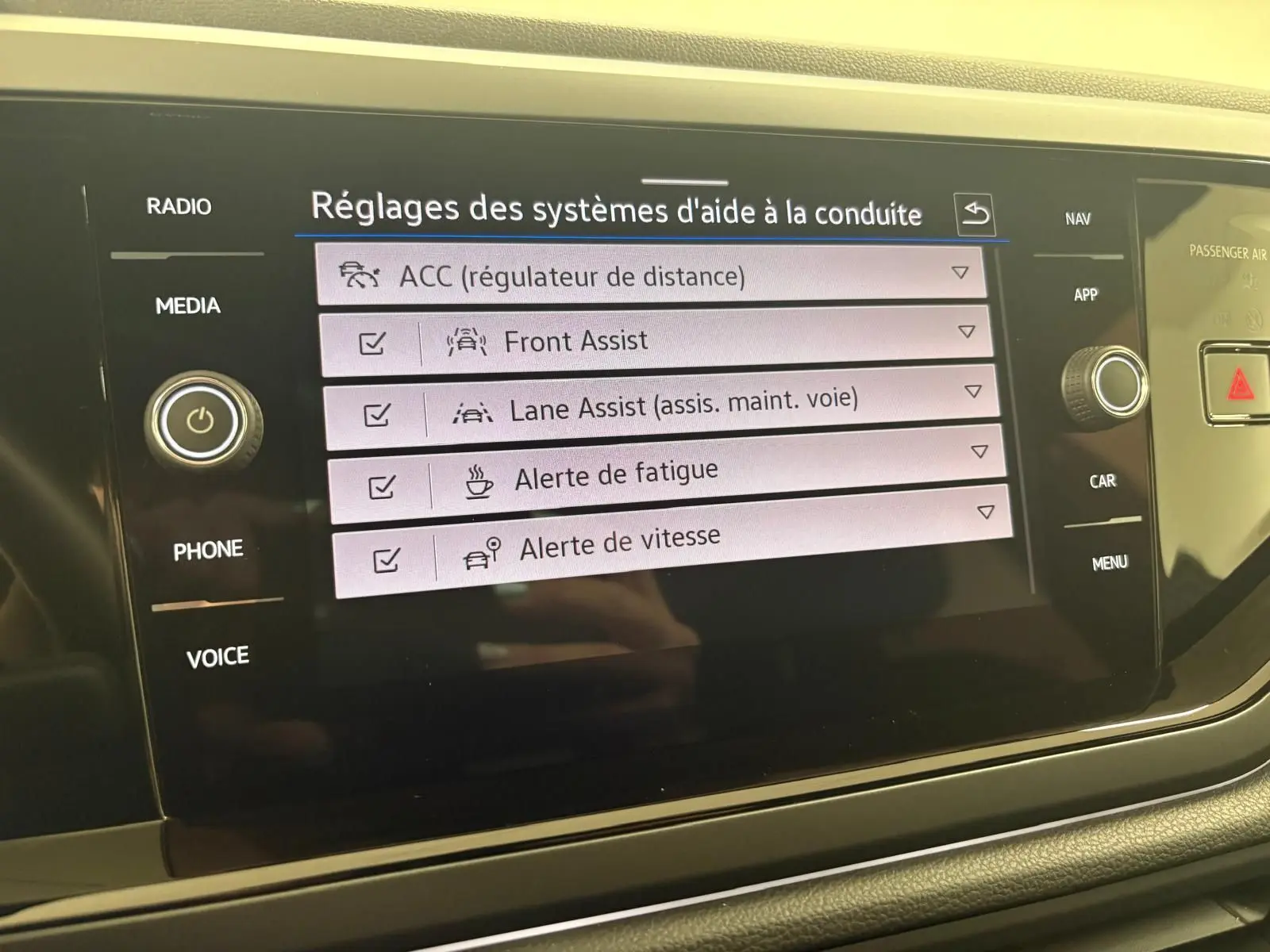 Écran tactile du système d'aide à la conduite du Volkswagen Taigo 2024 affichant les réglages d'assistances activées.
