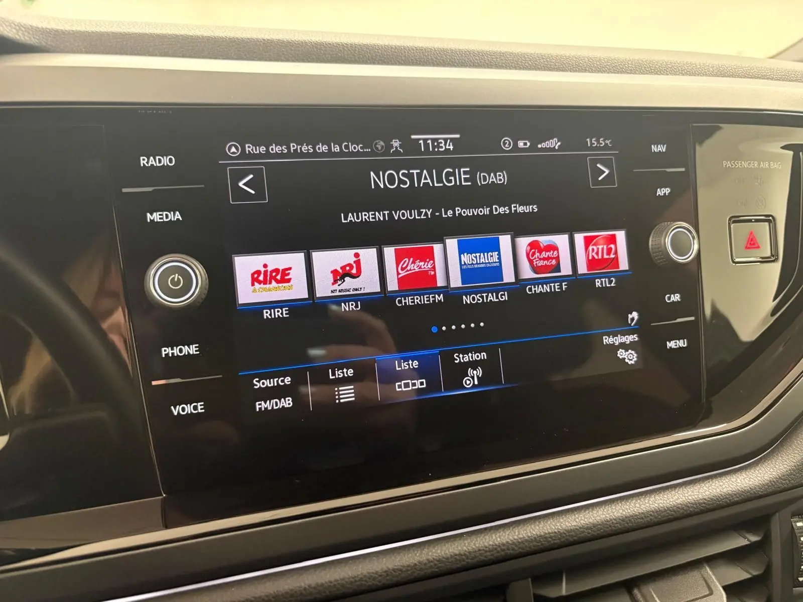 Écran tactile central du Volkswagen Taigo 2024 affichant les stations radio DAB, avec commandes autour et finition noire brillante.