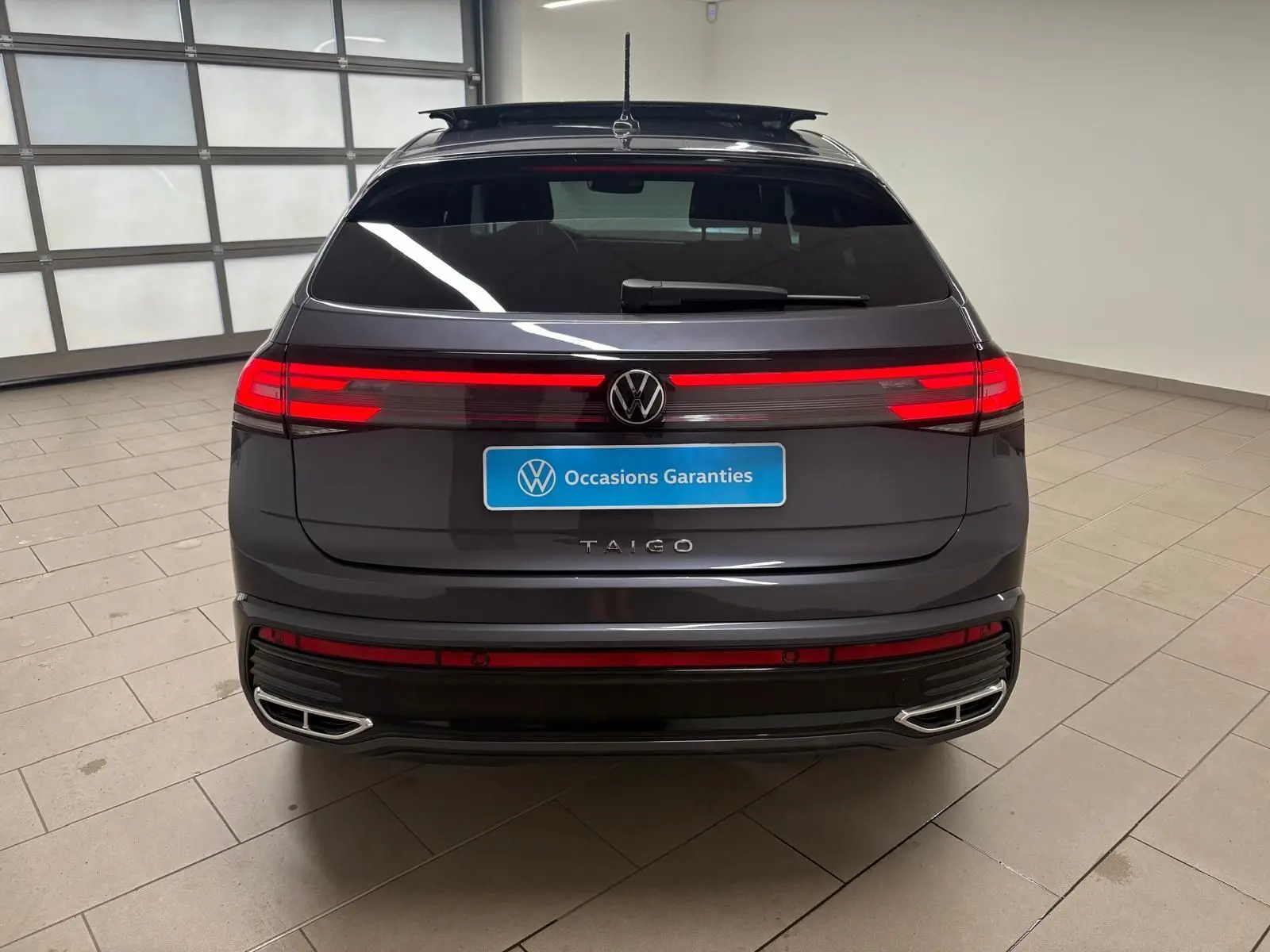 Vue arrière d'un Volkswagen Taigo gris cendré 2024 avec feux LED continus et double sortie d'échappement chromée.